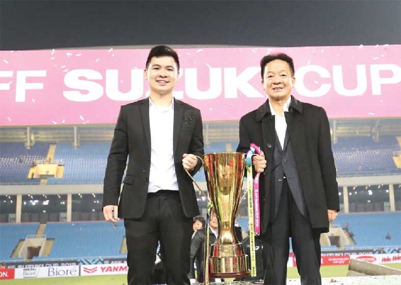 Đỗ Vinh Quang và cha mình là bầu Hiển cạnh chiếc Cúp vô địch AFF 2019